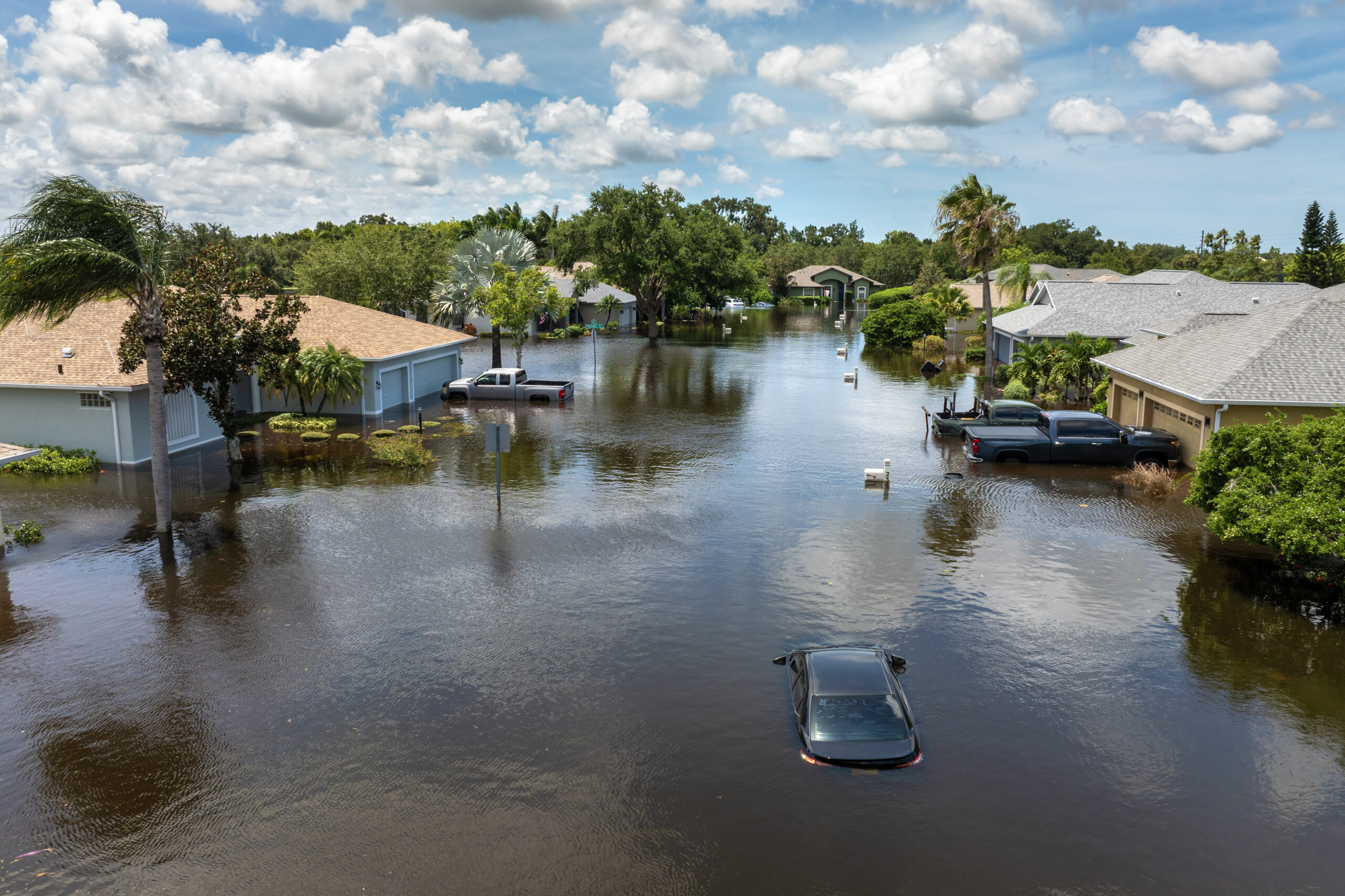 Flooded neighborhood with submerged cars and houses.