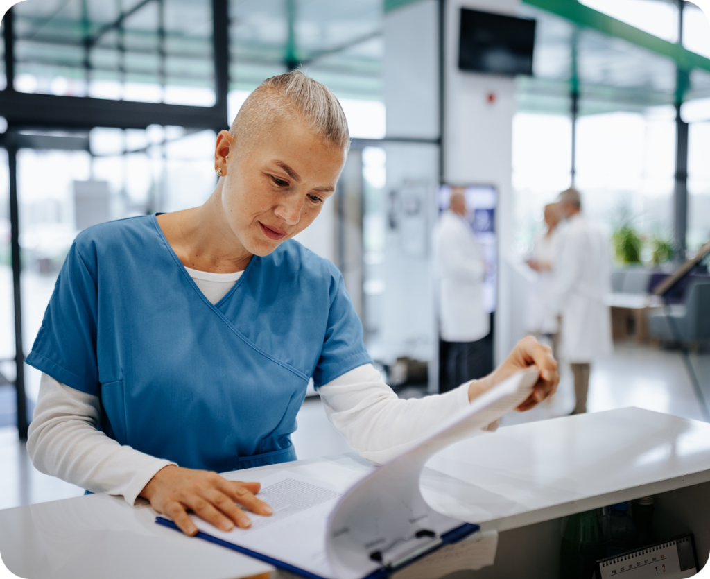 Nurse reviewing documents at hospital reception.